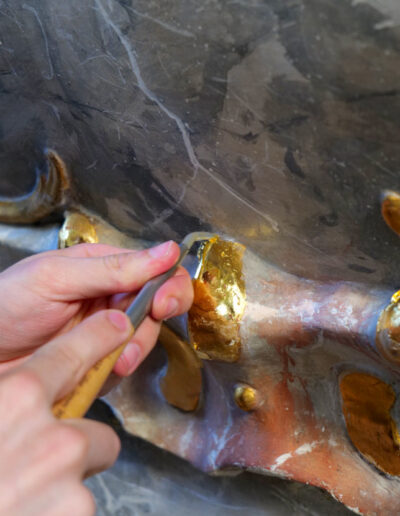 Detailaufnahme des Polierens von Blattgold mit einem Achatstein bei der Polimentvergoldung.
