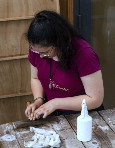 Chaska Schuler schärft einen japanischen Stechbeitel auf einem Wasserstein während der Summer School «Introduction to Japanese Carpentry» 2022.