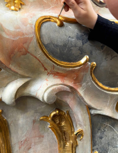 Restauratorin beim Retuschieren eines vergoldeten Altarornaments mit feinem Pinsel in der Pfarrkirche St. Michael Seehausen