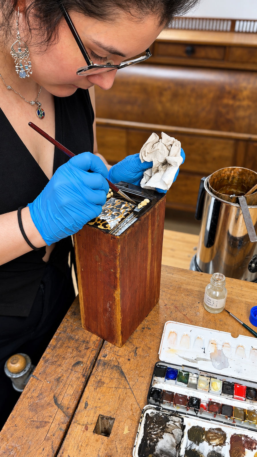Feinretusche an einem historischen Kabinettschrank Restauratorin Chaska Schuler retuschiert mit einem feinen Pinsel die ornamentale Verzierung eines historischen Möbelteils.